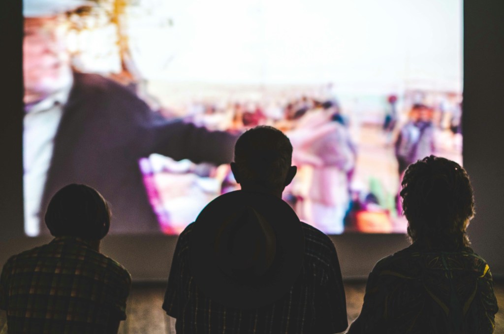 3 personnes devant un écran de cinéma